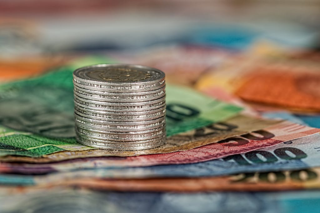 Pila monedas sobre billetes colores simbolizando finanzas y divisas