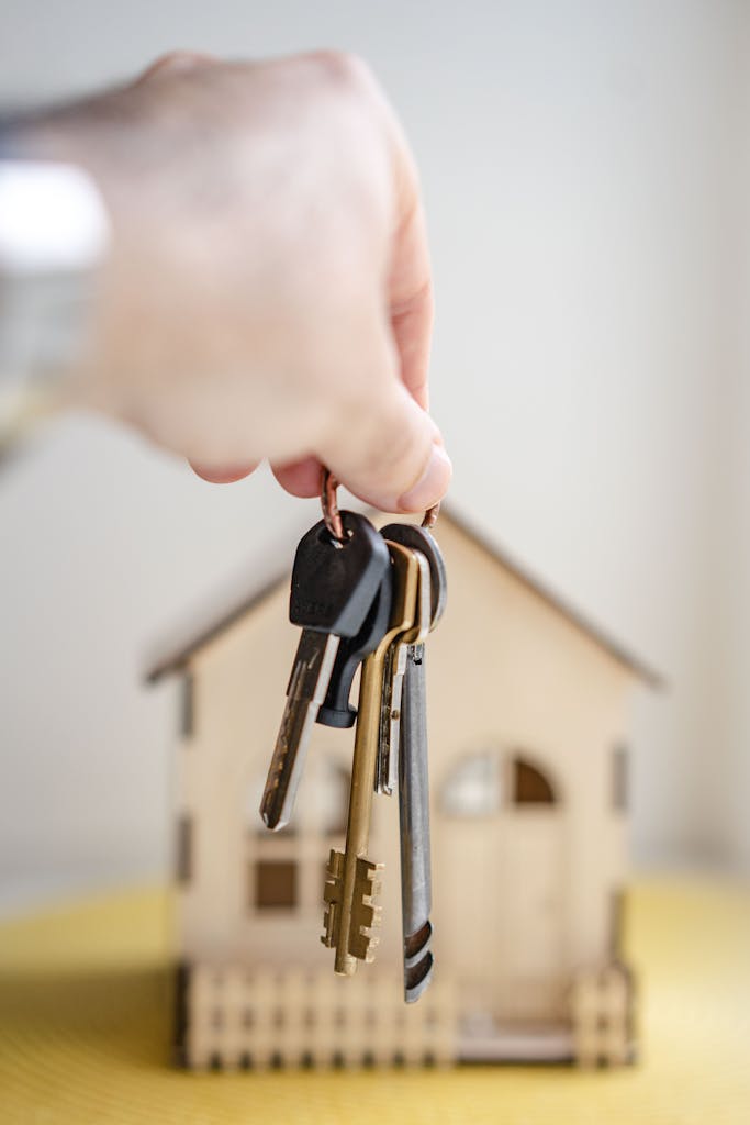 Mano sosteniendo llaves con casa miniatura simbolizando inversión inmobiliaria nuda propiedad